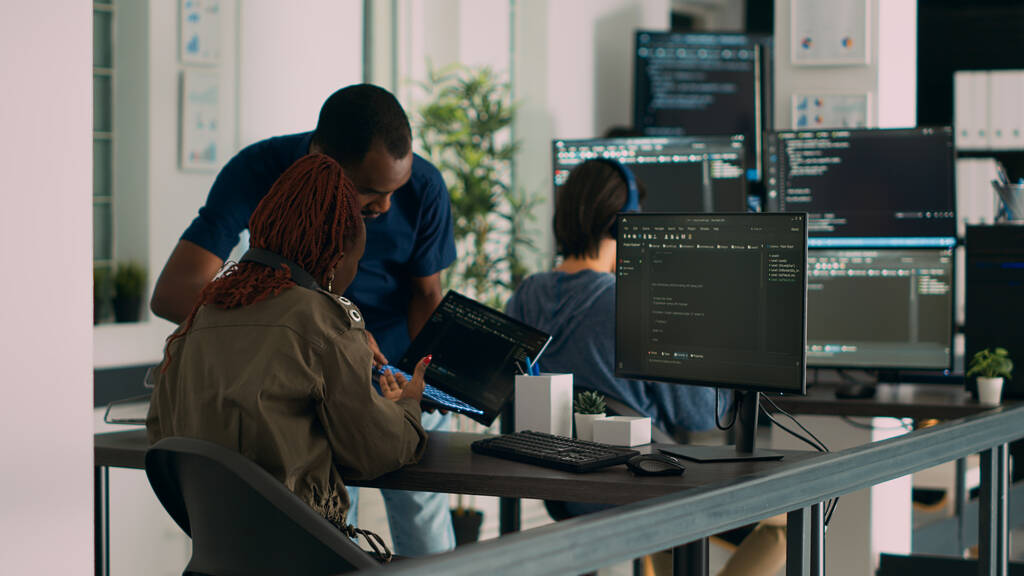 database developer explaining algorithm to colleague coder pointing at running code database developer explaining algorithm to colleague coder pointing at running code